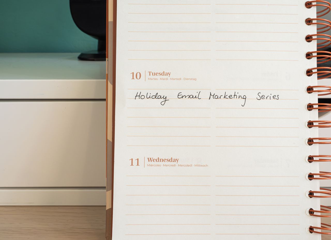 heros-img Planner open on a desk with handwritten Holiday Email Marketing Series note.